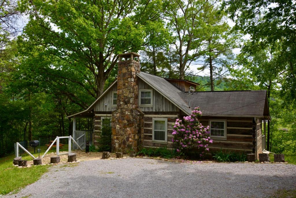 eine kleine Blockhütte mit einem gemauerten Schornstein und Blumen in der Unterkunft Bear Creek Cabin, Hot Tub, WIFI, Cozy Cabin Retreat in the Smokies Comfort & Fun for All in Sevierville
