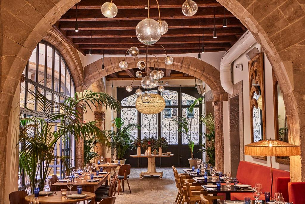 um restaurante com mesas e cadeiras de madeira e janelas em Puro Grand Hotel em Palma de Maiorca