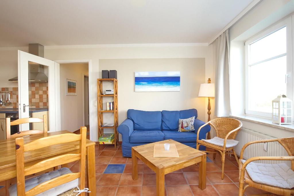 a living room with a blue couch and chairs at Dünenblick Wohnung 21 in Boltenhagen