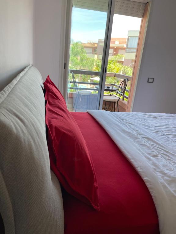uma cama vermelha e branca com vista para uma varanda em kechluxe em Marrakech