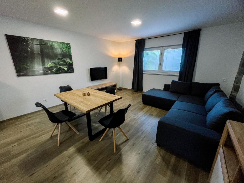 Apartment Neli في Rečica ob Savinji: غرفة معيشة مع أريكة زرقاء وطاولة