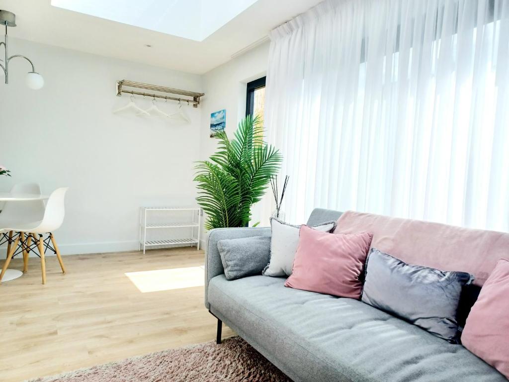 a living room with a couch with pink and grey pillows at 'The Limes' - Air-Con Two Double Bedroom Holiday House with Private Garden in Kent