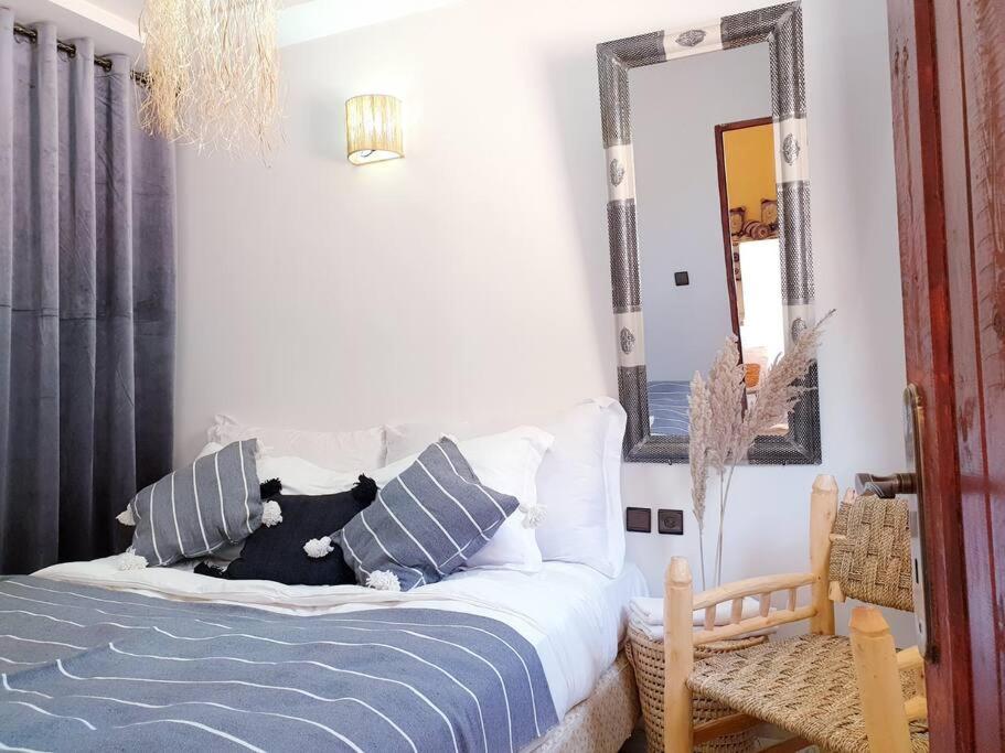 een slaapkamer met een bed met kussens en een spiegel bij Enjoy Sunsets at this Lovely & Romantic Gest House in Marrakesh