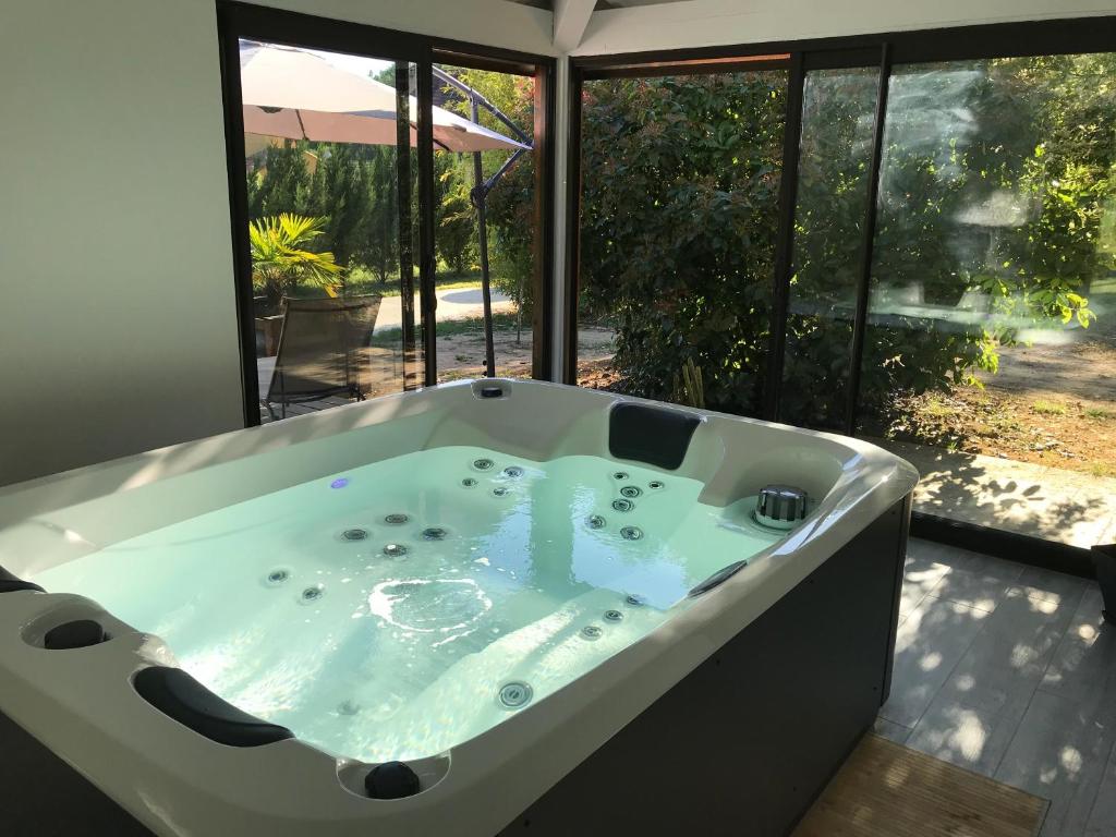 uma grande banheira num quarto com uma janela em Villa KIKO Spa & Sauna privatifs Gîte proche Sarlat em Vitrac