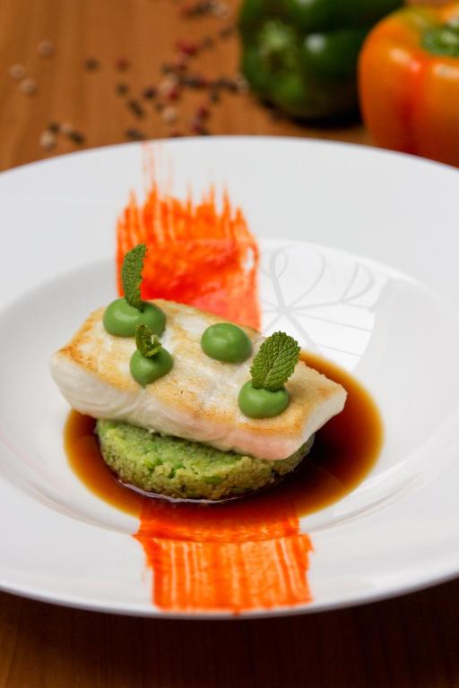 a white plate with a piece of fish with green toppings at Romantik Hotel Gasthaus Rottner in Nuremberg