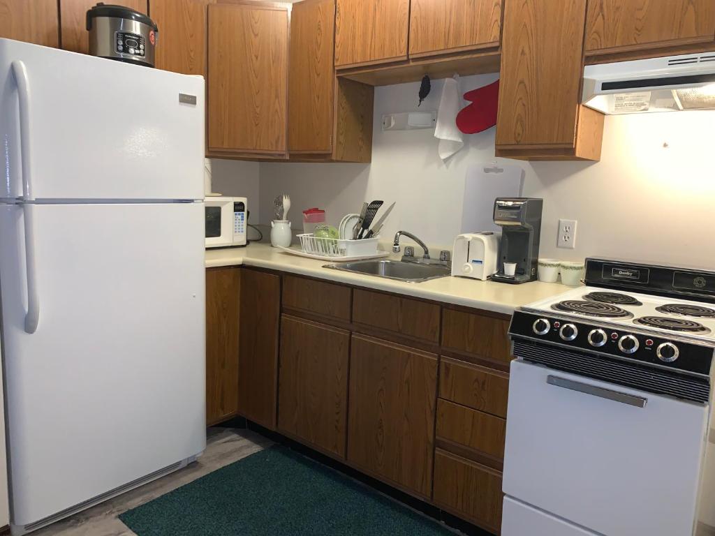 a kitchen with white appliances and wooden cabinets at Destination Family Hotel in Whitehorse