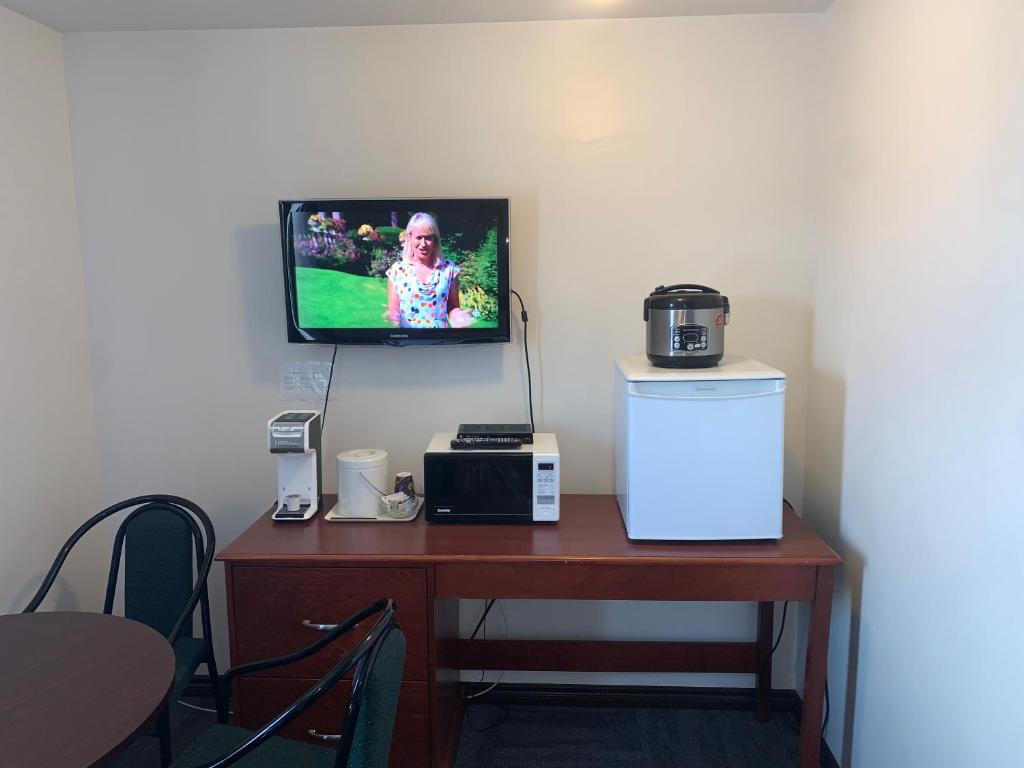 a room with a desk with a tv and a refrigerator at Destination Family Hotel in Whitehorse