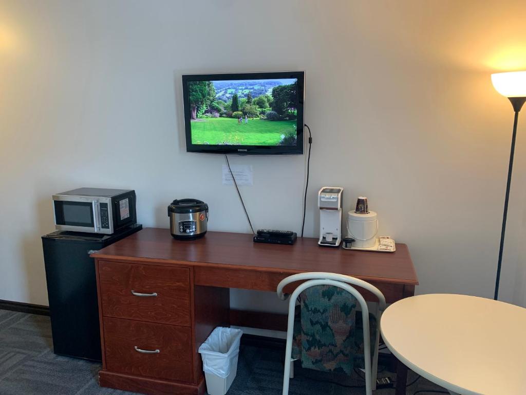 a desk with a microwave and a tv on a wall at Destination Family Hotel in Whitehorse