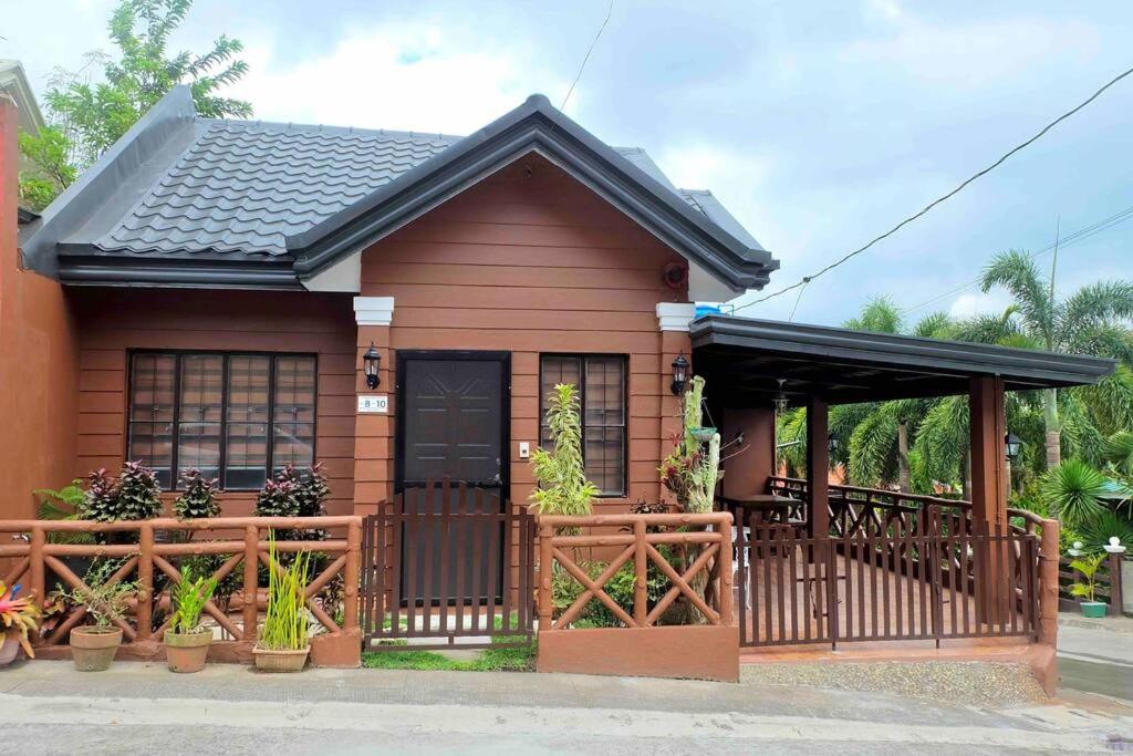 uma pequena casa com um portão e um alpendre em Cabin Hideaway, Alfonso Tagaytay em Alfonso