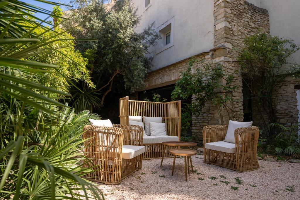 un groupe de chaises et de tables en osier sur une terrasse dans l'établissement Le Clos Violette et Le 11 D'Aglaé - Hôtel de Charme Design de Luxe, à LʼIsle-sur-la-Sorgue