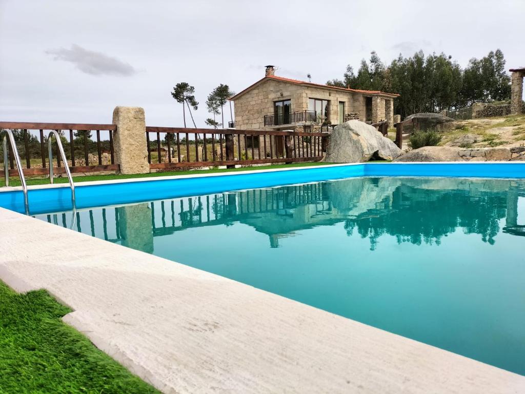 a blue swimming pool with a house in the background at Quinta Do Marmeiral in Mangualde