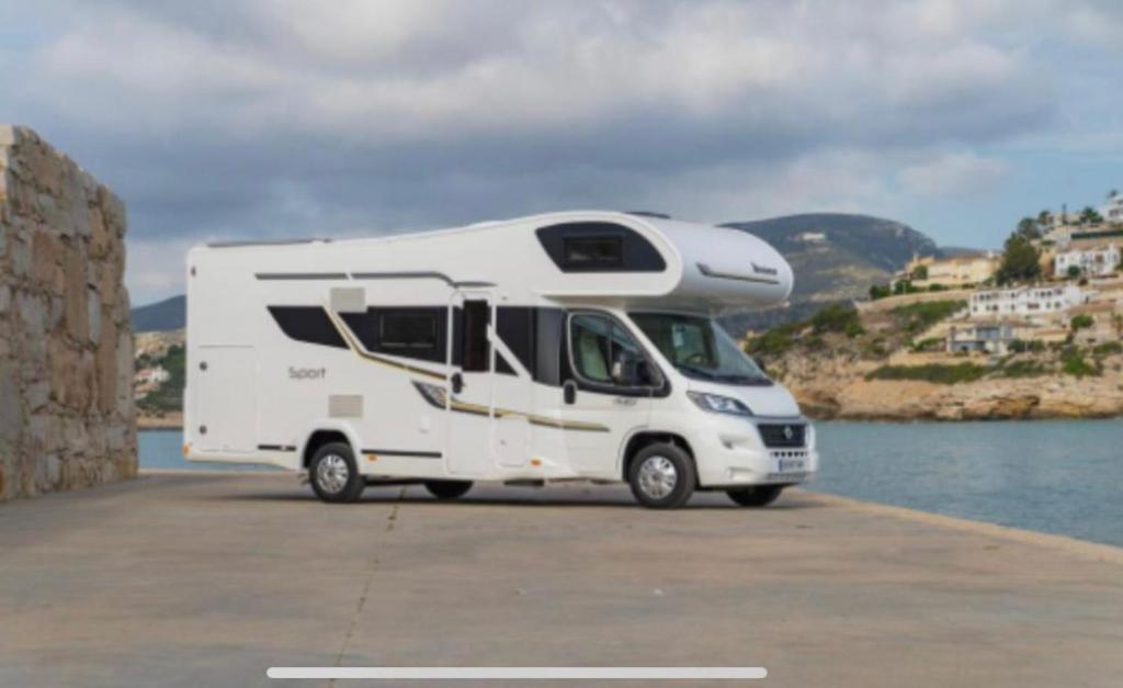 un camper bianco parcheggiato vicino all'acqua di Portugals Infinity - AutoCaravana Luxo a Faro