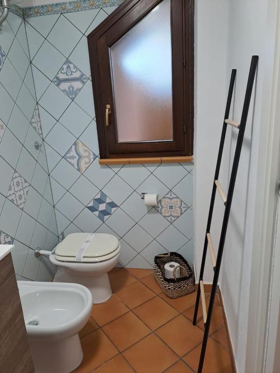 un bagno con un water, un lavandino e uno specchio di La Casa sulla Spiaggia a Marzamemi