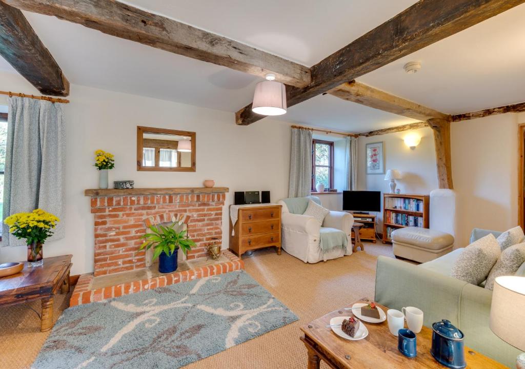 a living room with a brick fireplace and a couch at Leath Barn Cottage in Somerton