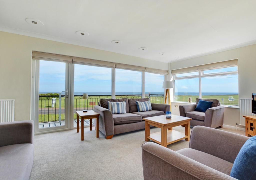 a living room with couches and a balcony with the ocean at 15 Clifton Park in Cromer