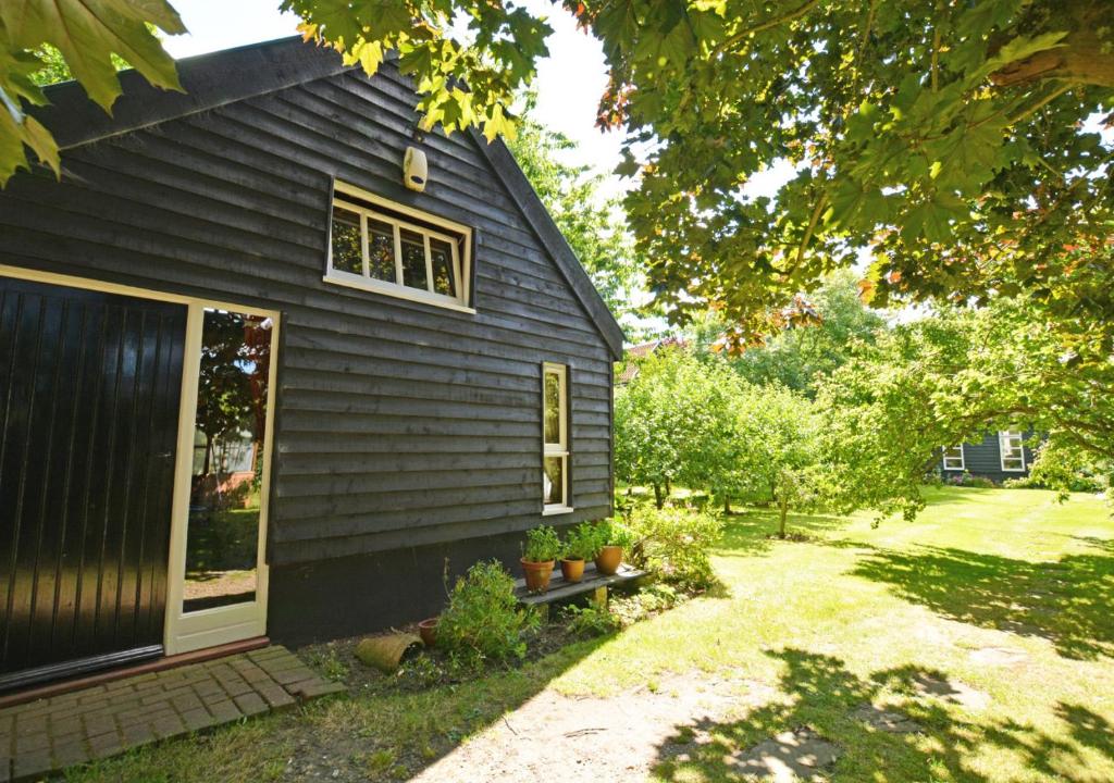 uma casa preta com uma janela e algumas plantas em Corner Barn em North Burlingham