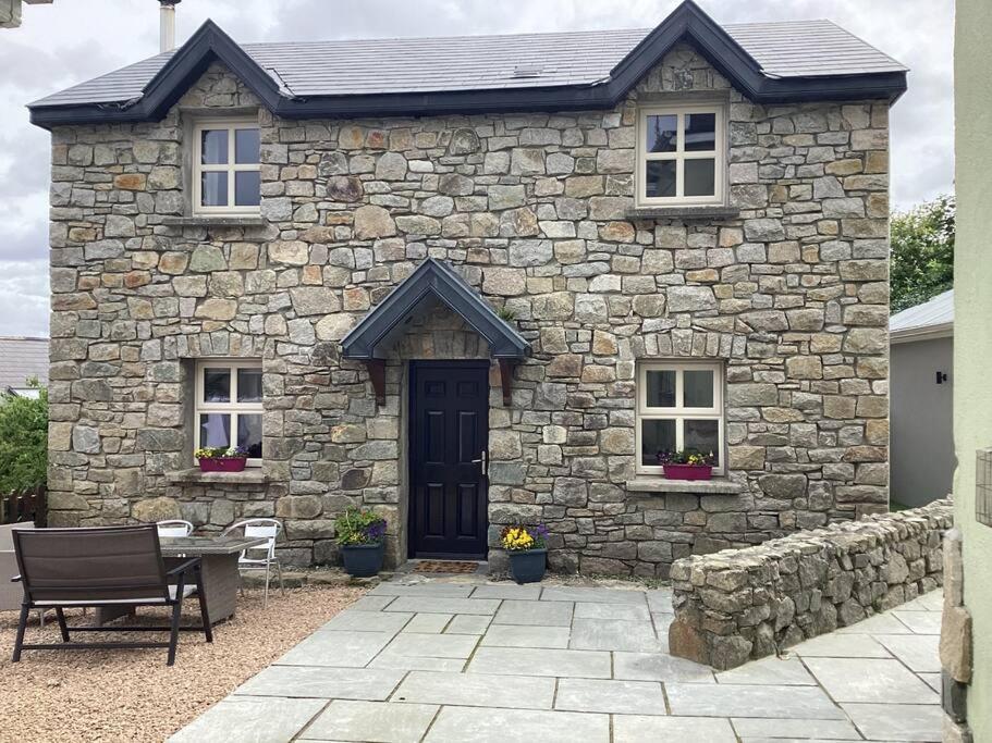 a stone building with a black door and two windows at Abby's Cottage Roundstoneselfcatering in Roundstone