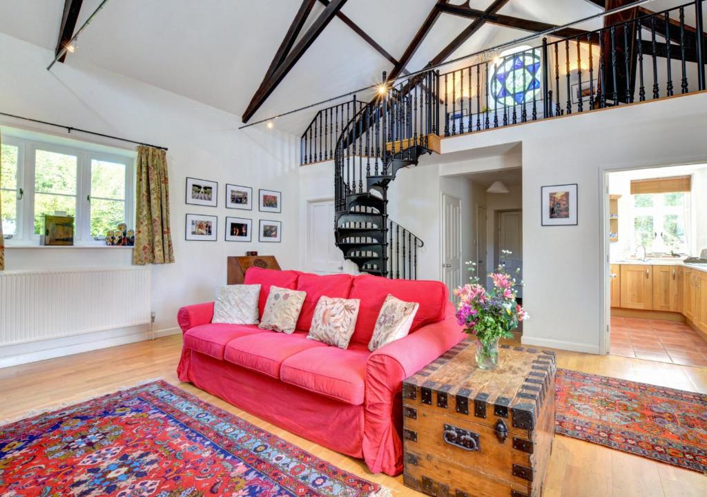 a living room with a red couch and a staircase at The Old Chapel in Hindolveston