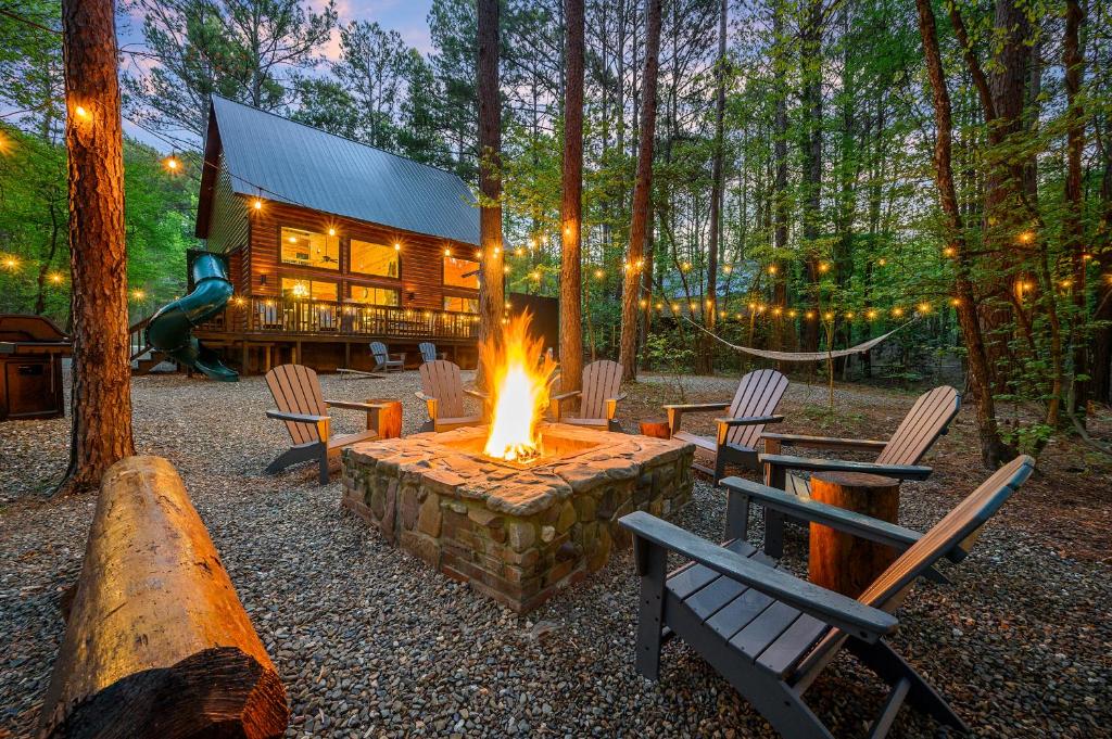 uma fogueira em frente a uma cabana de madeira em Hickory Bear - Cabin surrounded by pines, Sleeps 10, Hot Tub, Fire Pit, Arcade, Foosball Table & Deck Slide em Broken Bow