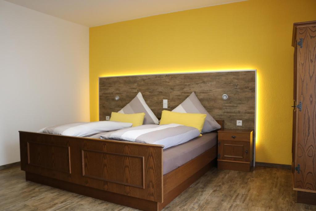 a bedroom with a large bed with yellow walls at Pension Selzer in Antrifttal