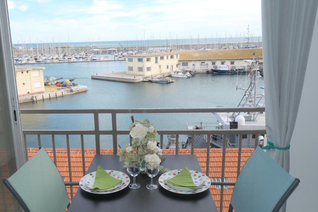 - une table avec des assiettes et des verres sur un balcon avec un port dans l'établissement Vue port et mer, centre-ville, au calme, garage, à Sète
