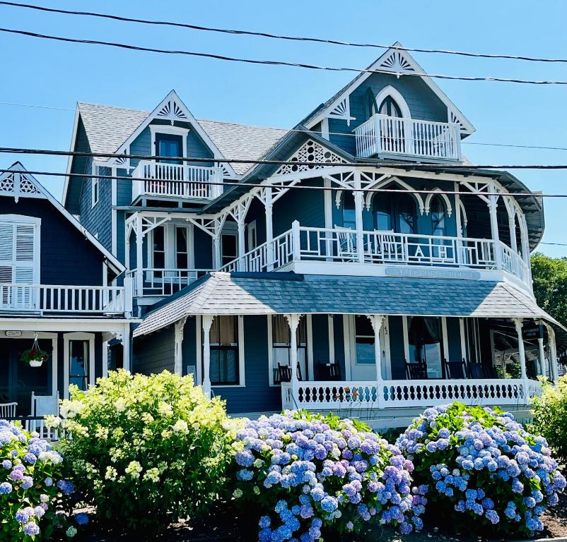een groot blauw huis met een veranda en bloemen bij The Attleboro House in Oak Bluffs