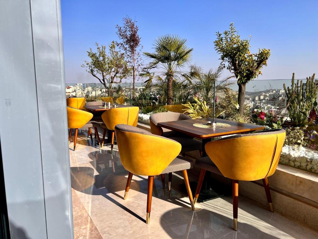 una fila de mesas y sillas amarillas en un patio en Reggenza Hotel Downtown Ramallah, en Ramallah