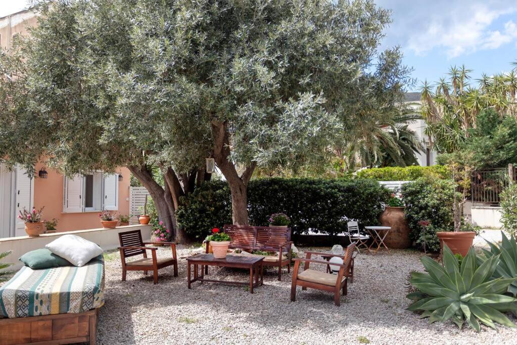 a patio with chairs and tables under a tree at Villa Marina Sant'Elia in Santa Flavia