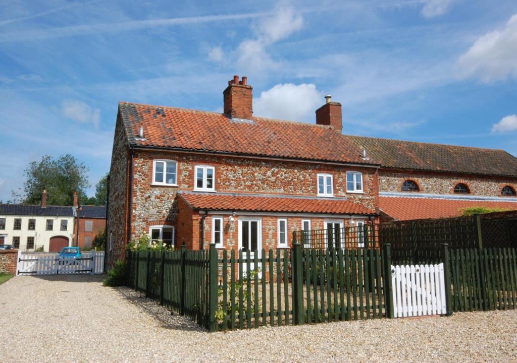 a large red brick house with a black fence at 17 The Green in East Rudham