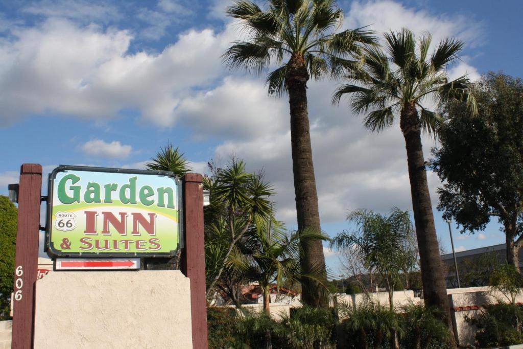 Garden Inn and Suites Glendora في غليندورا: وجود لافتة لنزل الحديقة والاجنحة بها نخيل
