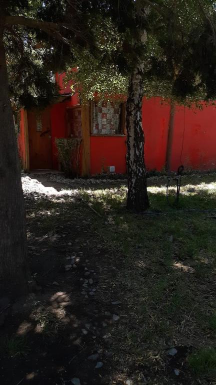 a red building with a tree in front of it at Cabaña km 12,7 in San Carlos de Bariloche