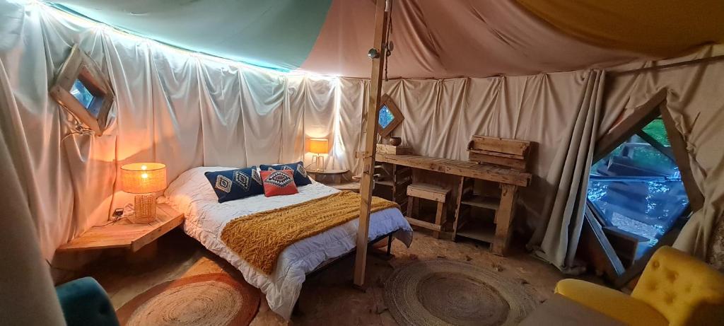 una camera con letto a baldacchino in una tenda. di Hebergement insolite, Location Yourte au bord du lac de mielan a Miélan