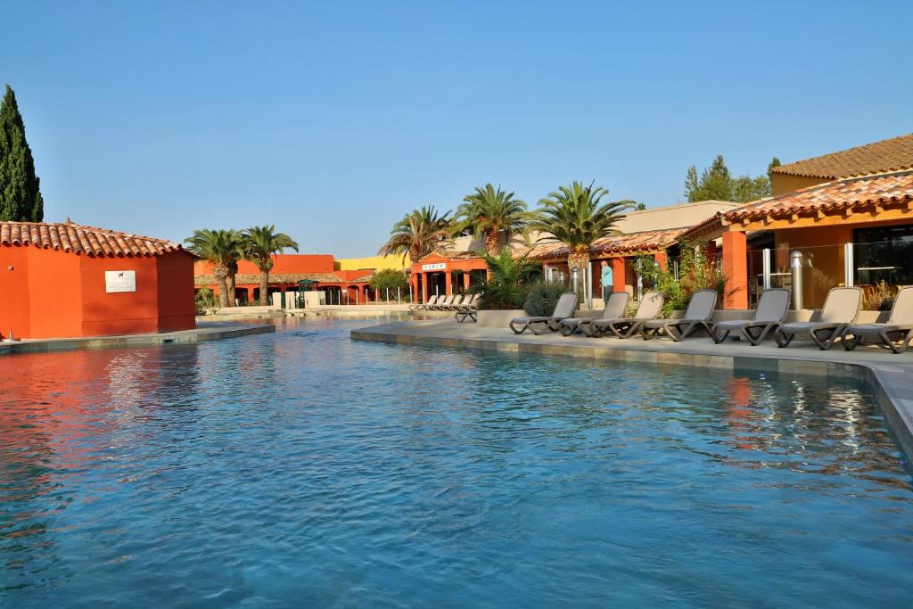 - une piscine dans un complexe avec des chaises et des bâtiments dans l'établissement SOWELL Family Les Amandiers, à Arles