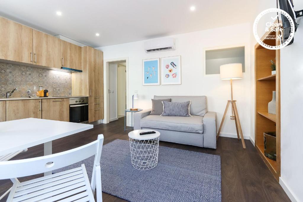 eine Küche und ein Wohnzimmer mit einem Sofa und einem Tisch in der Unterkunft Benfica Apartments I by Homing in Lissabon