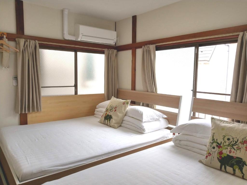 two beds in a room with two windows at Kiki HouseT --Self Check-in -- Room Number & Password is in the following email in Tokyo