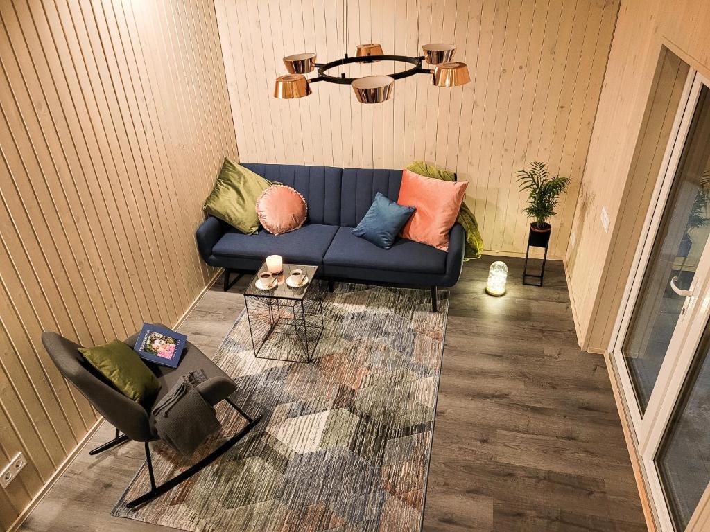 uma sala de estar com um sofá azul e uma cadeira em Holiday cabin BUUDA em Salacgrīva