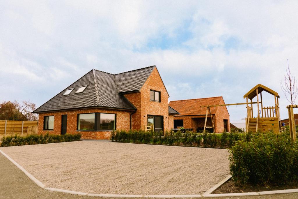 een stenen huis met een zwart dak bij Luxe Vakantiewoning De Veldhoek in Wingene