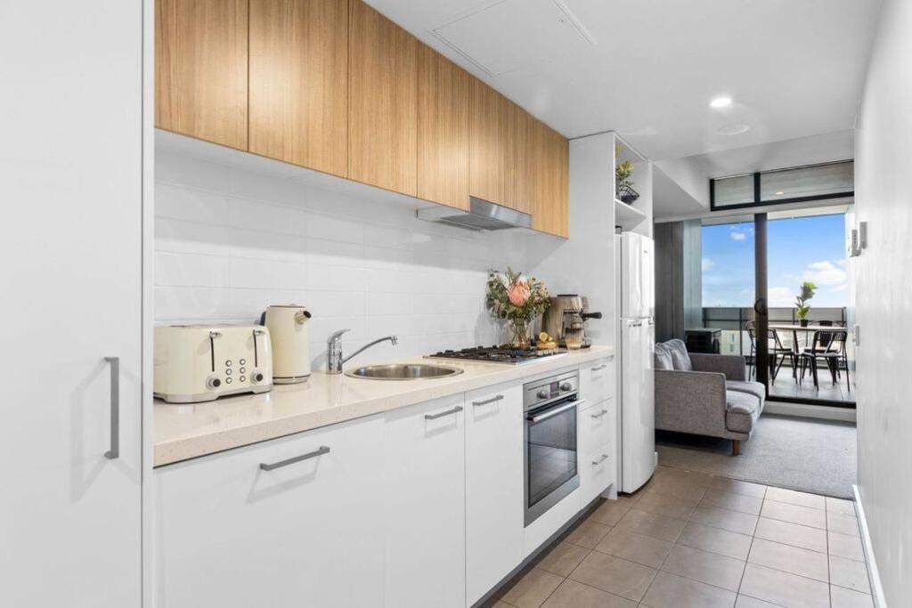 a kitchen with white appliances and a living room at Prestige 2bd Apartment Gym/Pool in Adelaide