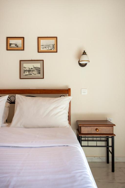 a bedroom with a white bed and a nightstand with a table at Villa Kalomira in Spetses