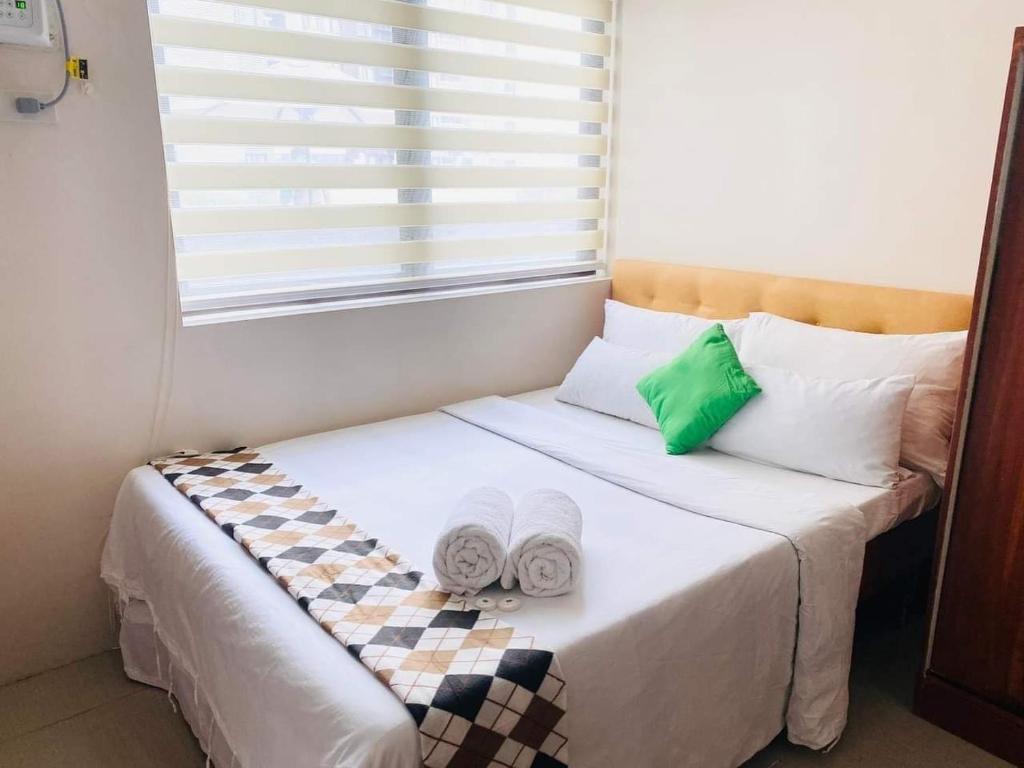 een bed met twee handdoeken en een raam bij Persimmon Condominium Cebu City in Cebu City