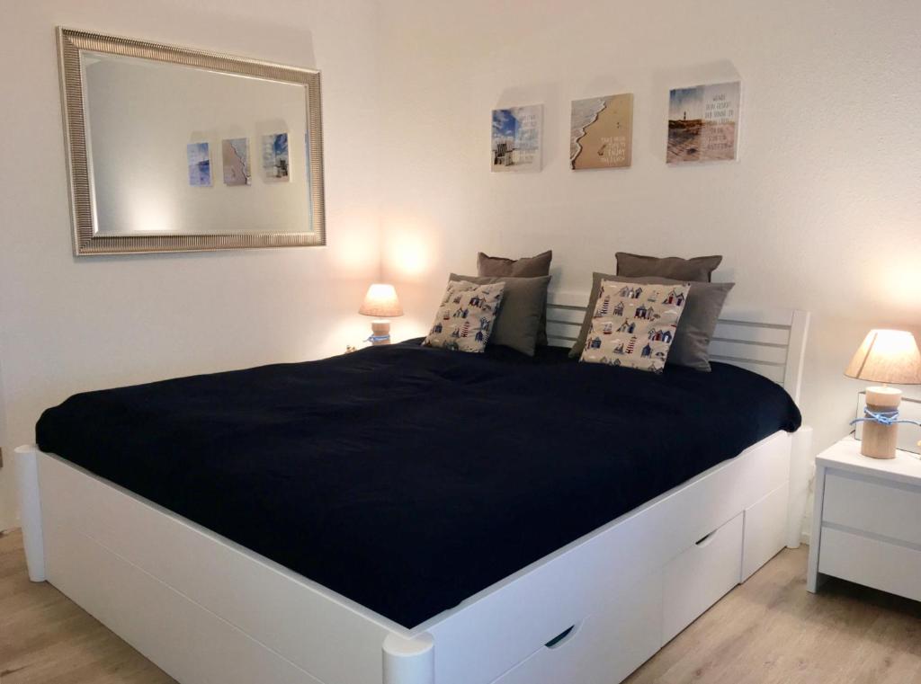 ein Schlafzimmer mit einem großen Bett mit schwarzer Bettwäsche und Kissen in der Unterkunft Burgtiefe Südstrand "Sorglos" in Fehmarn