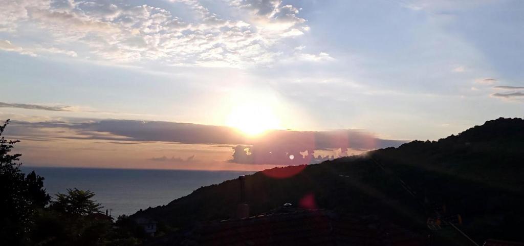 a sunset over a mountain with the sun in the sky at Anastasia's Cottage in Pelion in Makrirrákhi