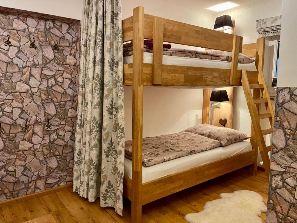a bedroom with bunk beds with a stone wall at Ferienwohnung Brandmaier in Unken