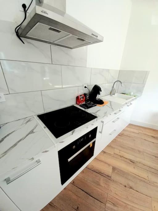 Il comprend une cuisine blanche équipée d'une cuisinière et d'un four micro-ondes. dans l'établissement Le scandinave de Vendargues, à Vendargues