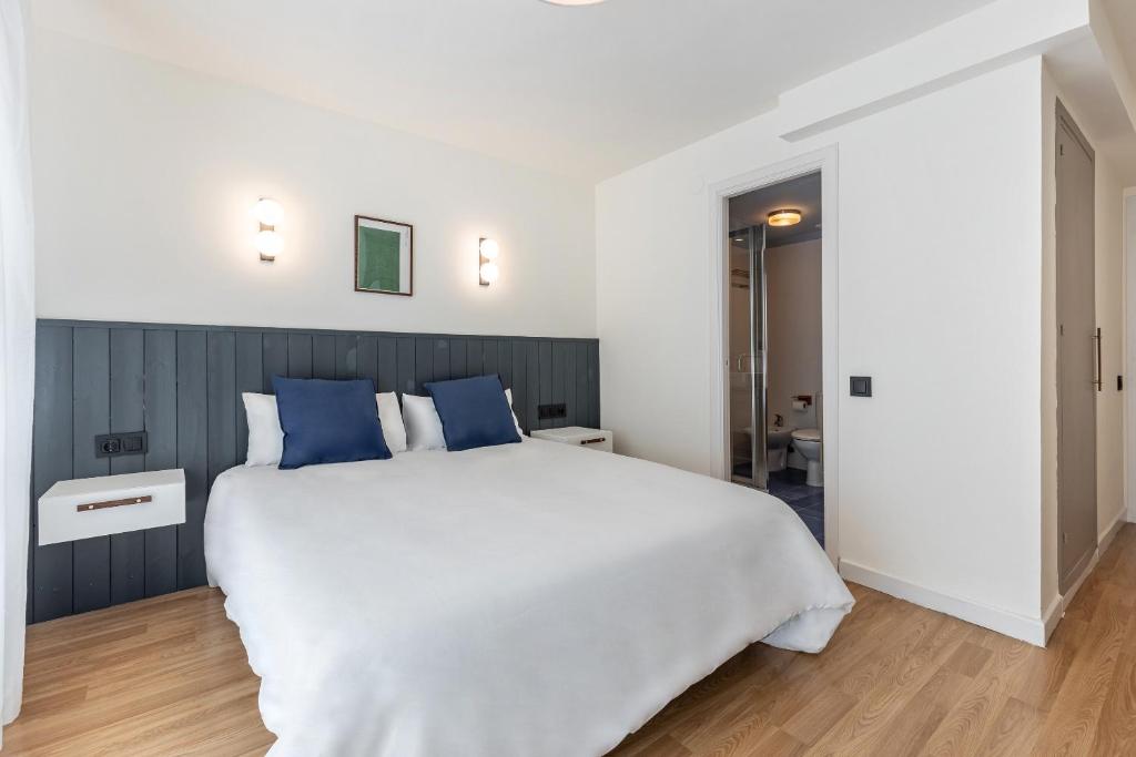 1 dormitorio con 1 cama blanca grande con almohadas azules en Granada Suites by Olala Homes, en Granada