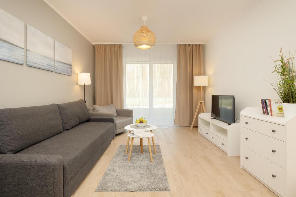 a living room with a couch and a tv at Plażowa Park Apartment with Garden by Renters in Międzywodzie