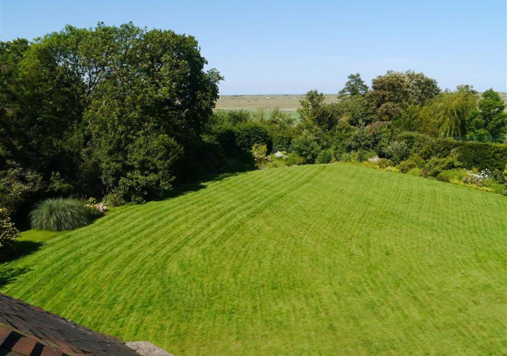 a large green grassy hill with trees in the background at 4 Dormy House in Brancaster