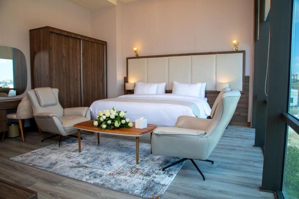 Pokój hotelowy z łóżkiem, 2 krzesłami i stołem w obiekcie Jeddah Homes Boutique Hotel w mieście Amman