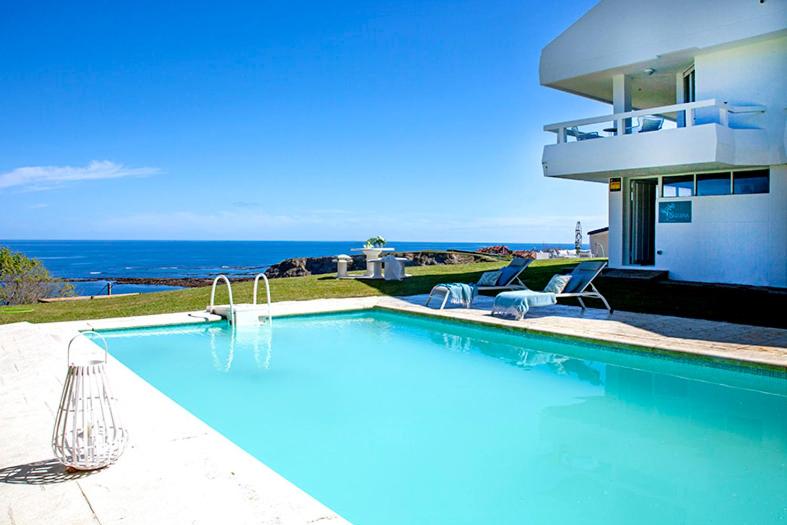 una piscina con due sedie e una casa di Impresionante villa sobre el mar en el mismo Comillas a Comillas