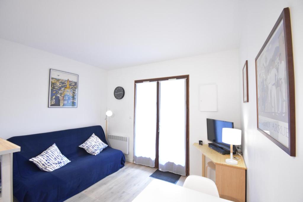 un salon avec un canapé bleu et une télévision dans l'établissement Balcons du port - Capbreton - A proximite immédiate du port de plaisance, studio en rez de chaussée avec cour dans résidence, à Capbreton